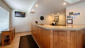 A modern kitchen with wooden cabinets, a granite countertop, and a built-in sink. There is a clock on the wall and a flat-screen TV mounted above the counter. - Trailside Inn (Alturas)