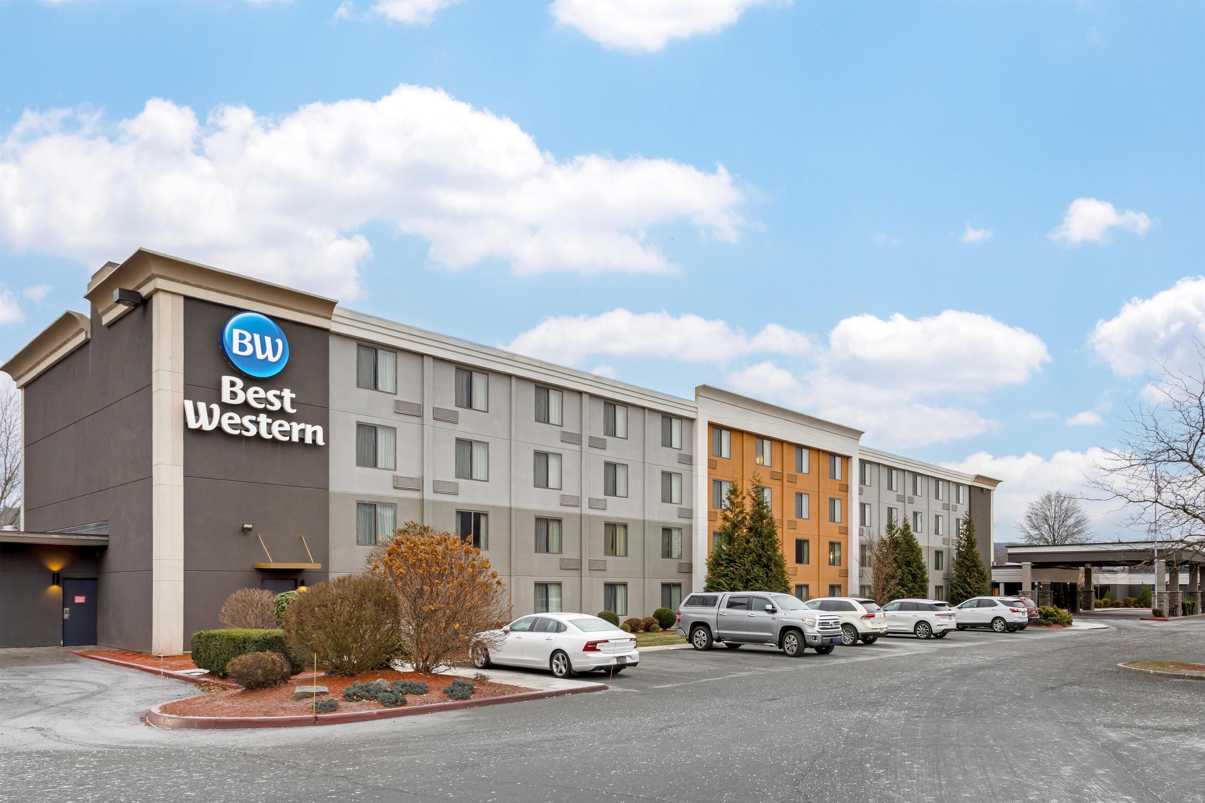 A Best Western hotel with a parking lot, multiple cars, and a clear sky.