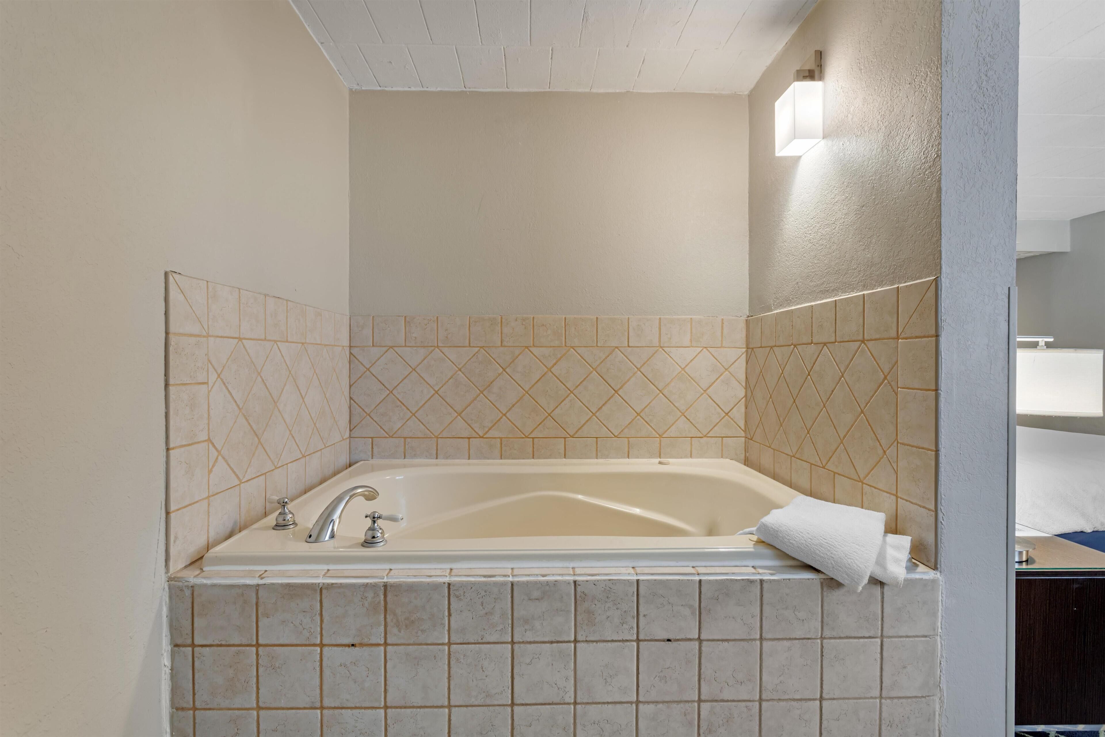 A bathroom with a bathtub, tiled walls, and a light fixture.