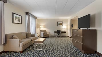 Ein Hotelzimmer mit Sofa, Schreibtisch, Stuhl, Fernseher und Kommode.