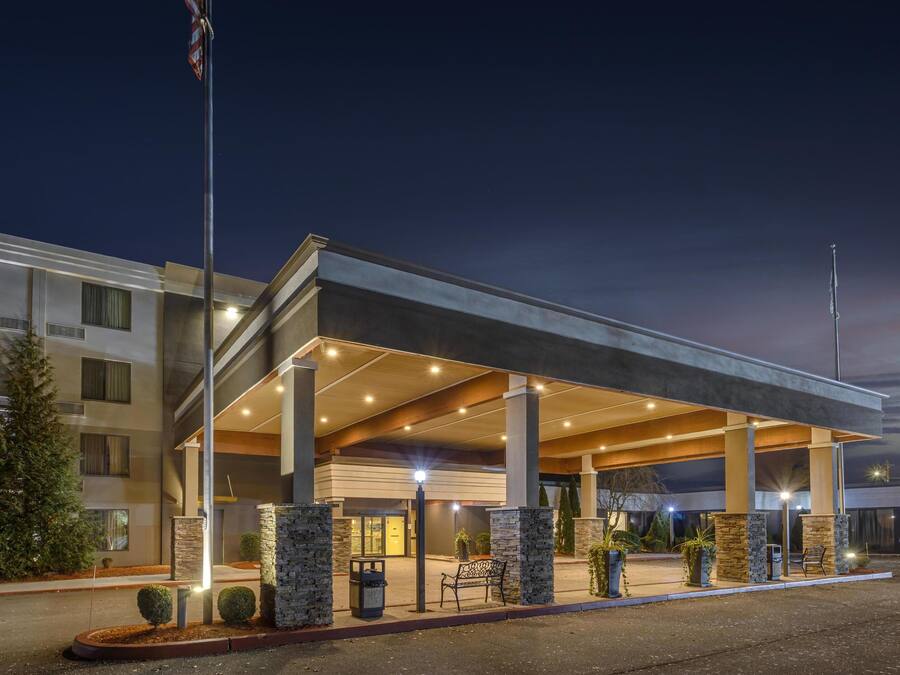A hotel with a covered entrance, stone pillars, and a flagpole.