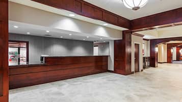 A reception area with a wooden reception desk, a grey textured wall, and a tiled floor.