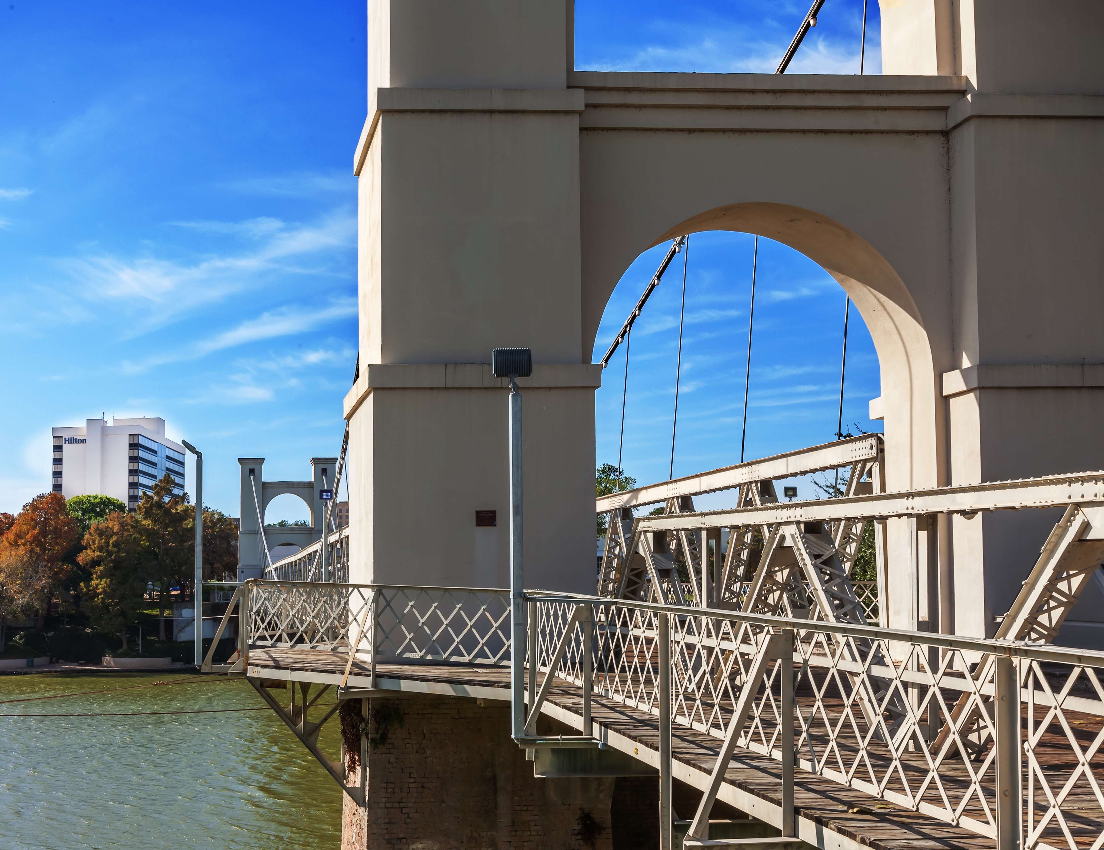 Eine Brücke mit Fußgängerweg und Blick auf ein Hilton Hotel im Hintergrund.