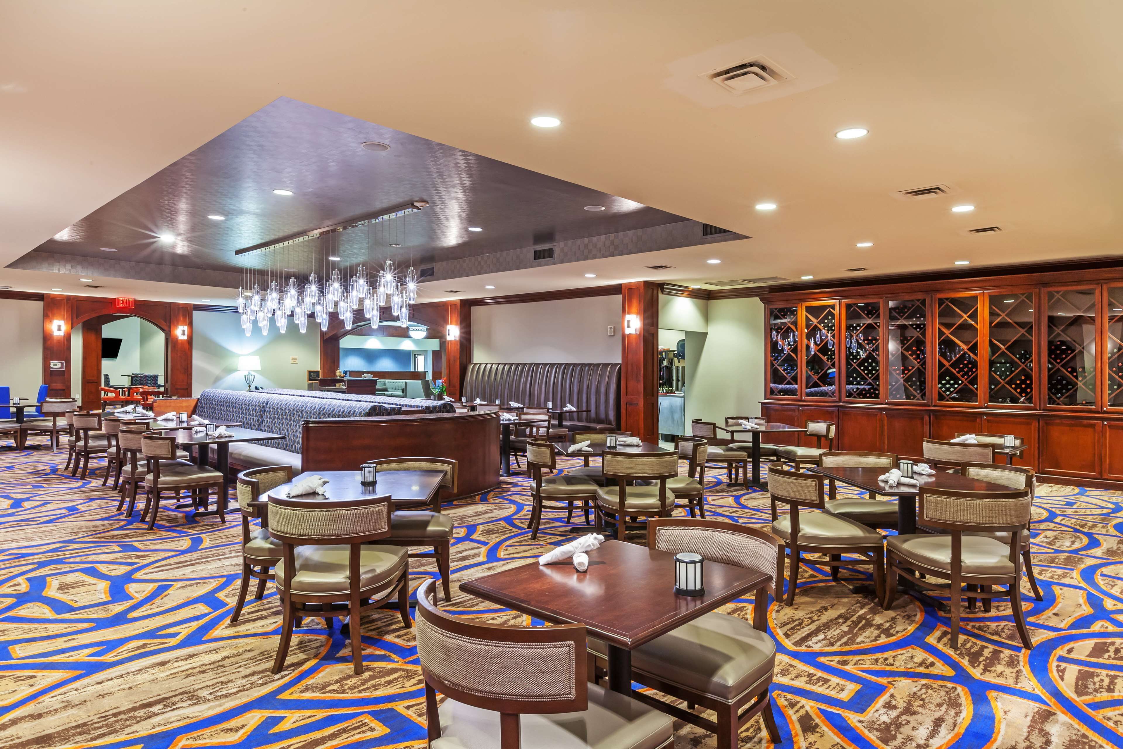 A hotel lobby with a large seating area, a reception desk, and a wine display.