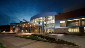 A modern building with a curved facade, large windows, and a covered entrance area. - Hilton Waco (Waco)
