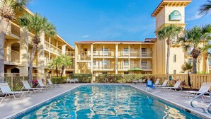 Un hotel con piscina, varios balcones y palmeras.