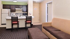 A compact living space with a kitchenette, a sofa, and a patterned floor.