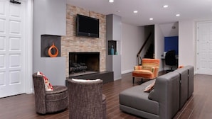 Ein modernes Wohnzimmer mit Kamin, grauen Sofas und einem Flachbildfernseher.