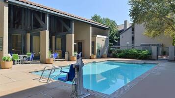 A swimming pool with a lifeguard stand, lounge chairs, and a covered patio area.