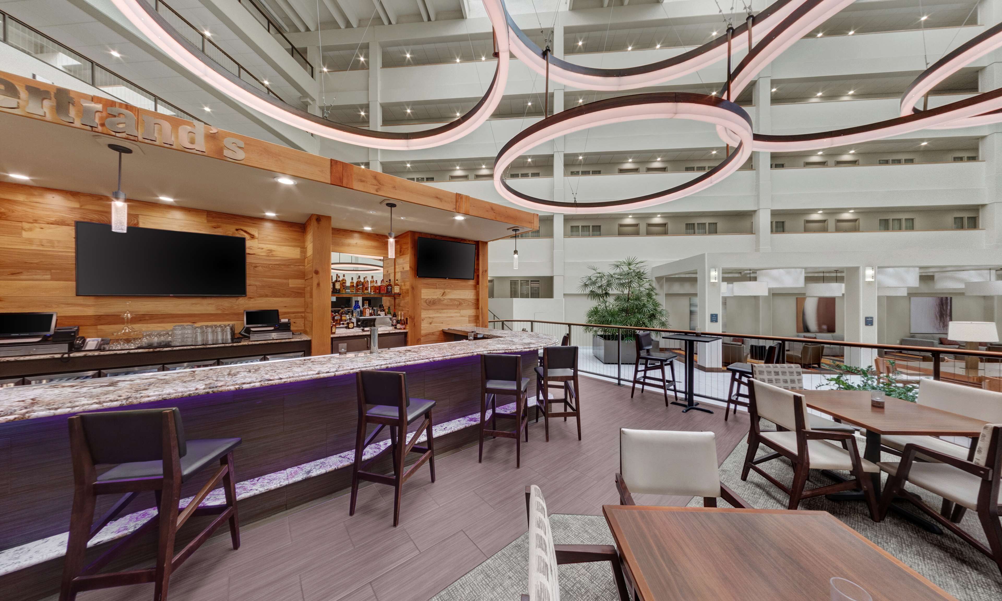 Una hall moderna di un hotel con area bar, posti a sedere e vista sui piani superiori.
