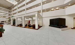 A spacious lobby with multiple levels, a central seating area, and a large dark water feature. - Embassy Suites by Hilton Milwaukee Brookfield (Brookfield)
