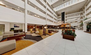 A spacious lobby with multiple seating areas, a central staircase, and a high ceiling with skylights. - Embassy Suites by Hilton Milwaukee Brookfield (Brookfield)
