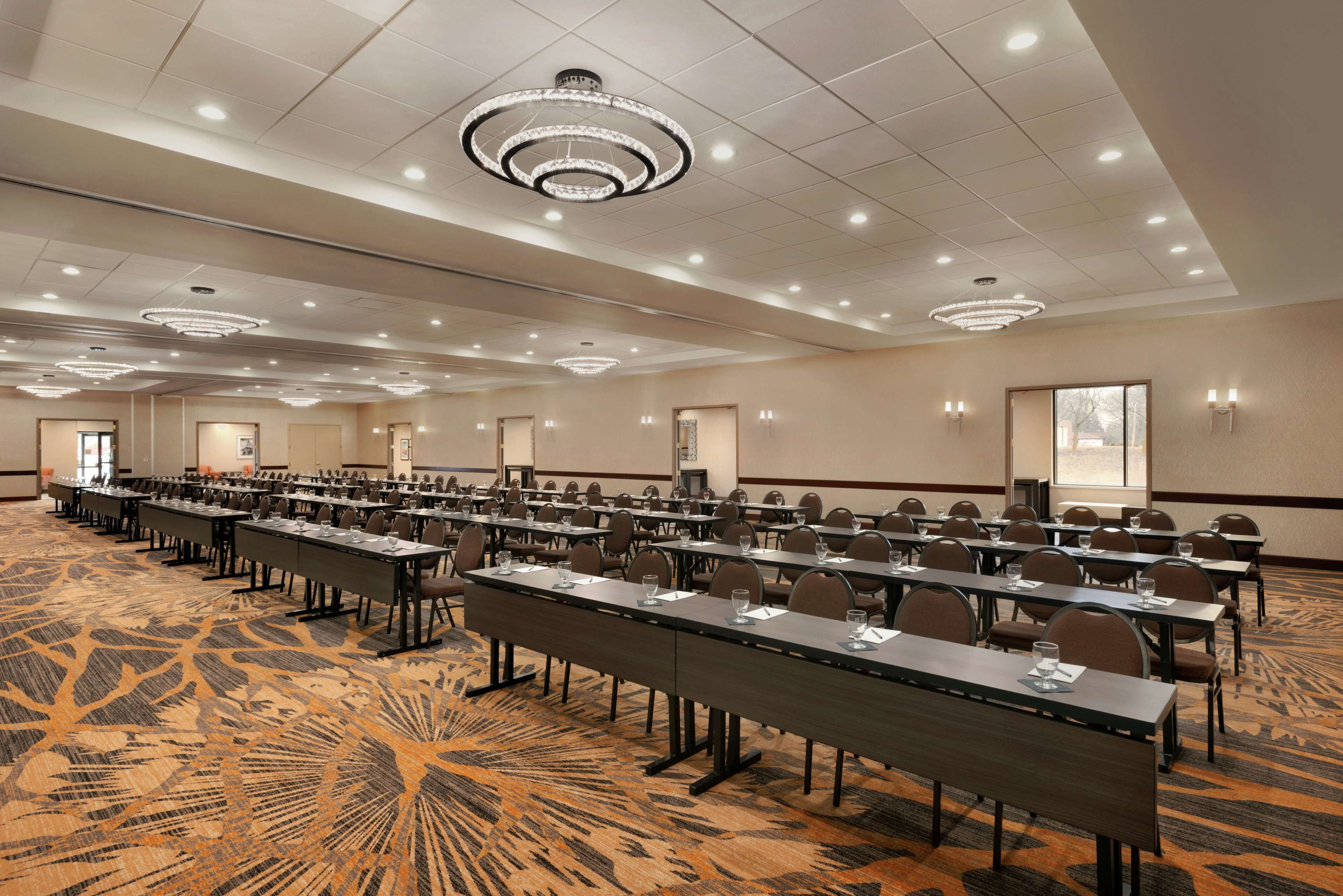 A conference room with multiple tables, chairs, and a carpeted floor.