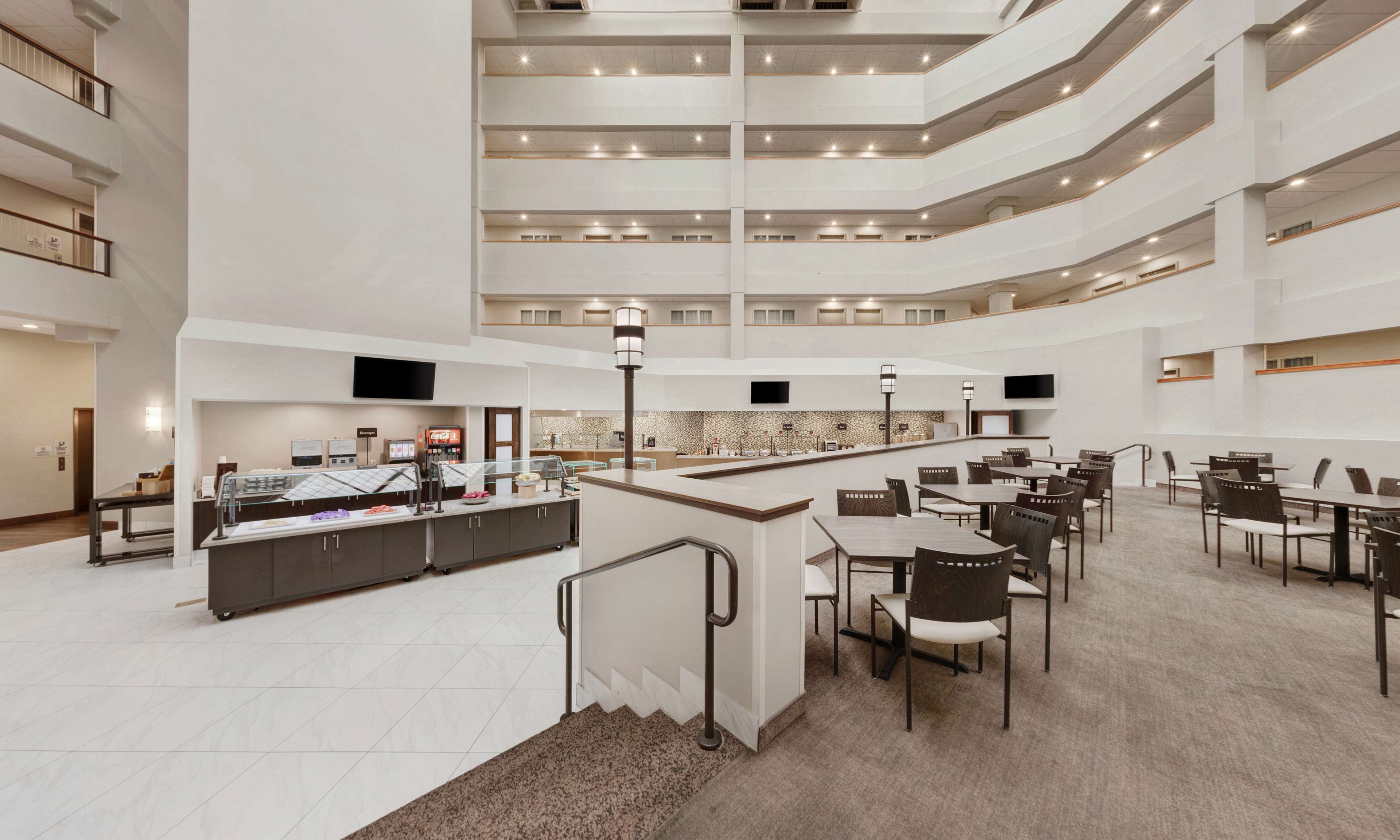 A multi-level hotel lobby with a central bar area, seating arrangements, and a modern design.