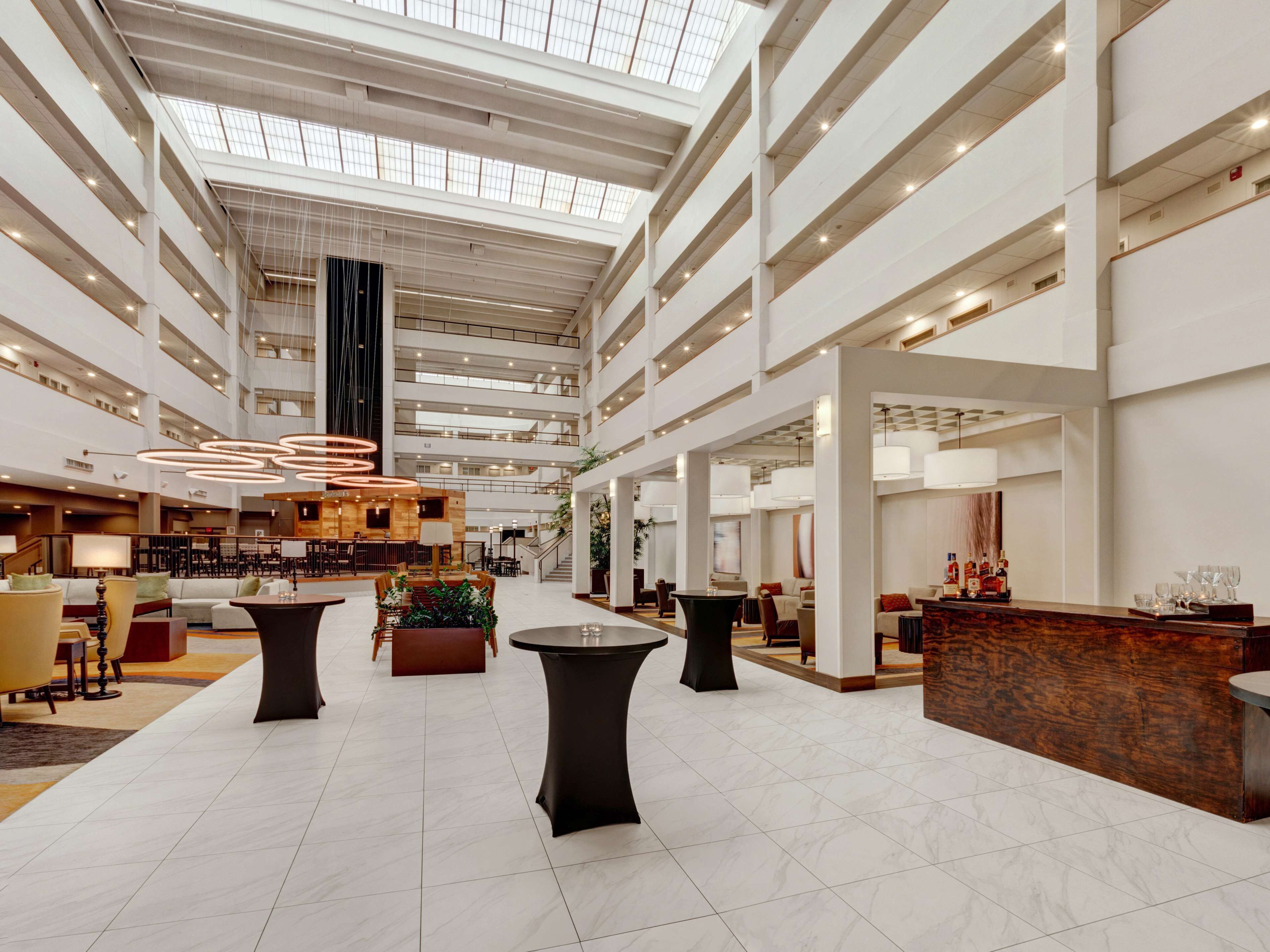 A spacious hotel lobby with multiple seating areas, a reception desk, and a high ceiling with skylights.