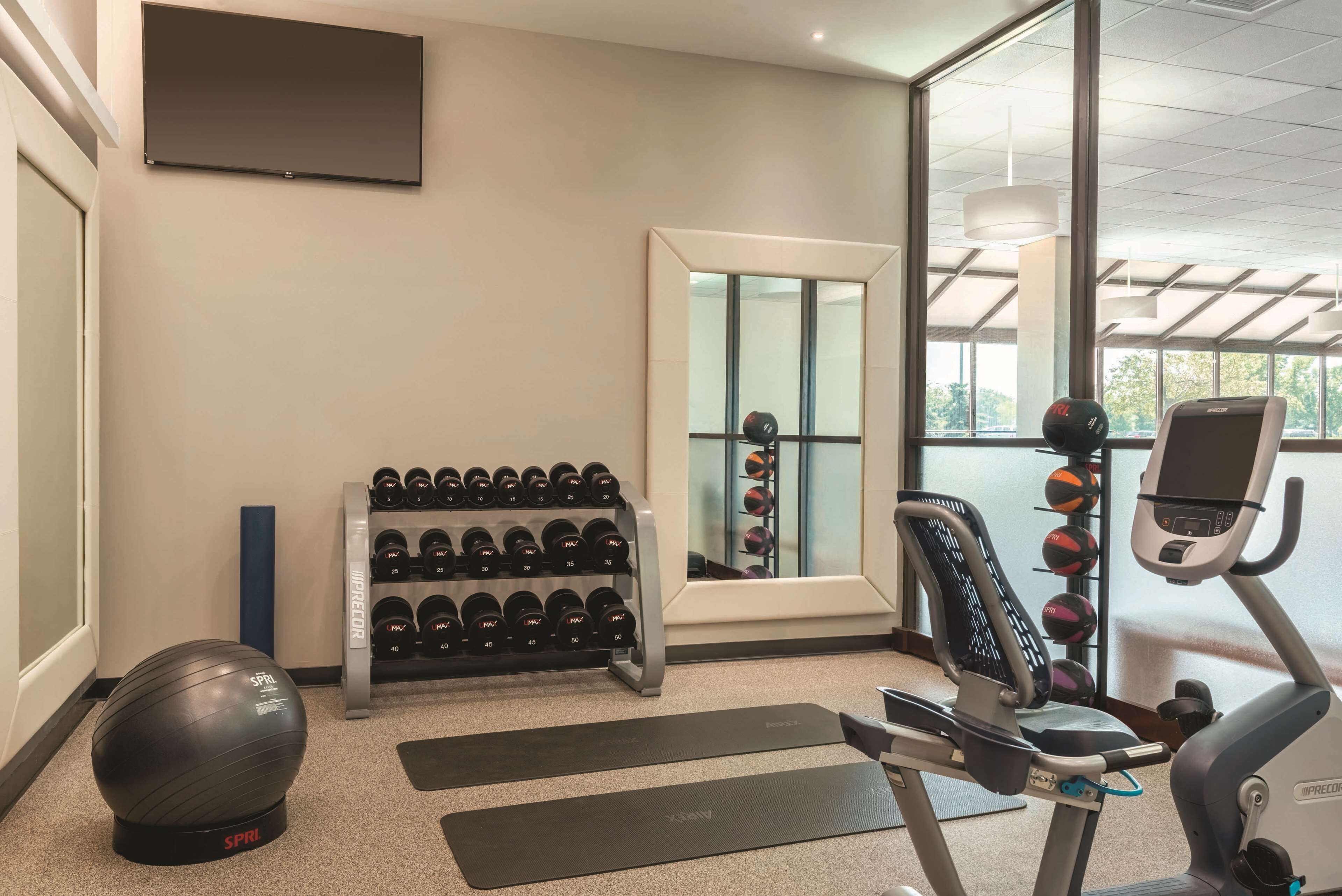 A gym with exercise equipment, a mirror, and a window with a view.