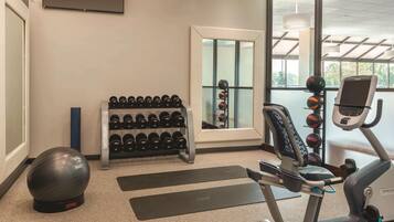 A gym with exercise equipment, a mirror, and a window with a view.