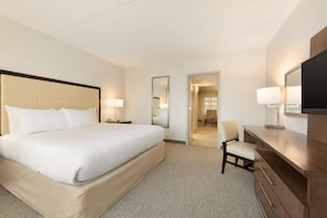 A hotel room with a large bed, a desk with a chair, a TV, and a mirror.