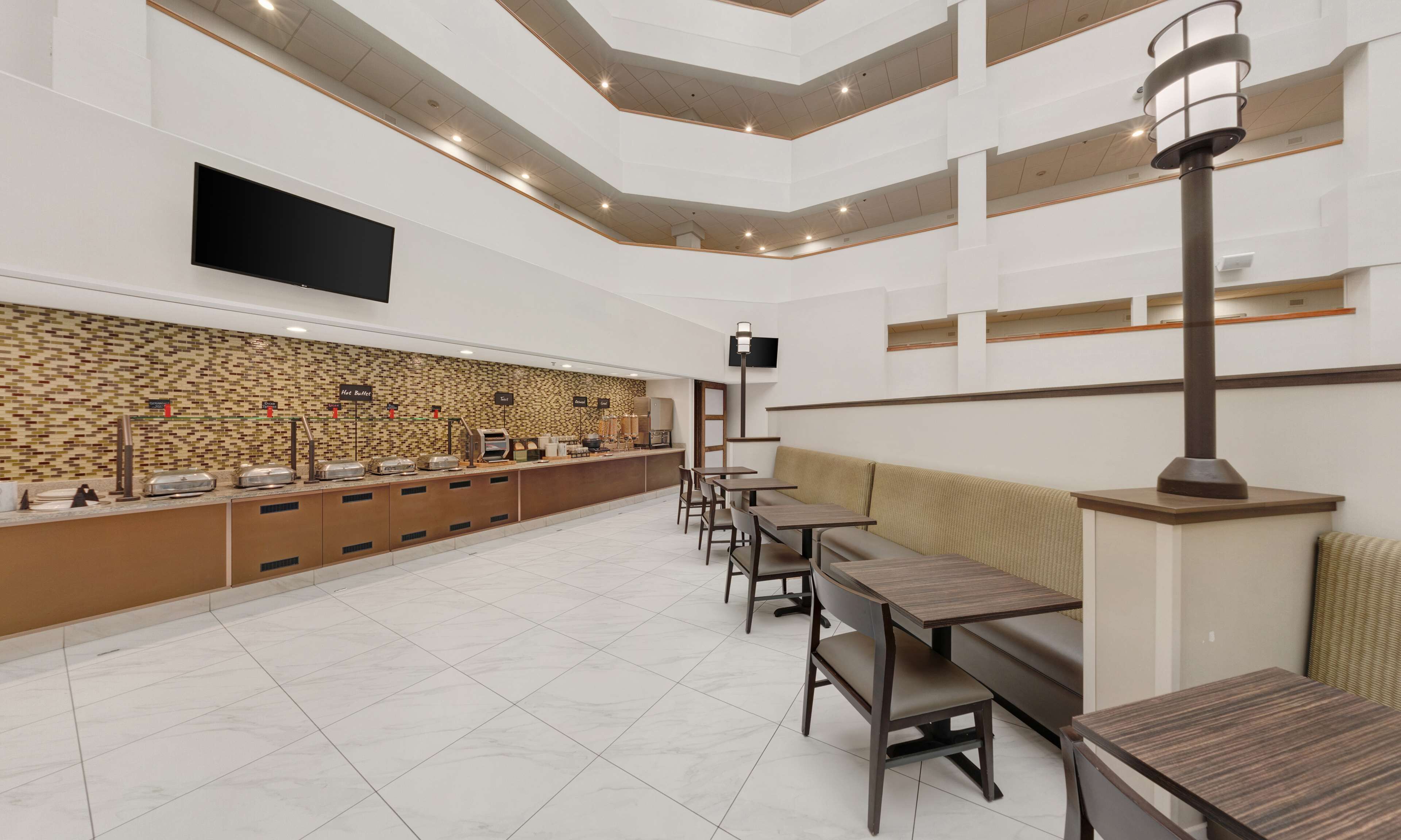 Ein modernes Restaurant mit Buffet, Sitzgelegenheiten und einem wandmontierten Flachbildfernseher.