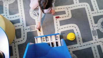 Een kind speelt met autootjes op een speelkleed met een patroon.