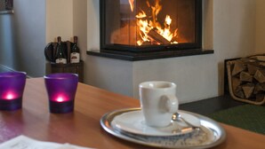 A fireplace with a visible fire, a table with a newspaper, and two cups.