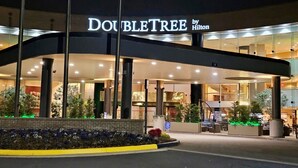 A hotel entrance with a sign reading 'DOUBLETREE by Hilton' and a covered area with columns. - DoubleTree by Hilton Washington Dulles Airport (Herndon)