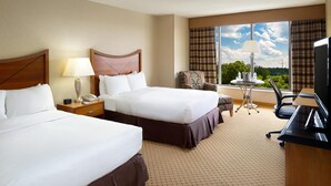 A hotel room with two beds, a desk, a chair, a lamp, and a view of the outdoors. - DoubleTree by Hilton Washington Dulles Airport (Herndon)