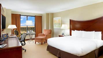Una habitación de hotel con una cama grande, un escritorio, una silla, una mesita y un televisor.