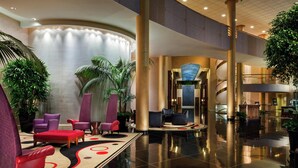 A spacious lobby with a curved wall, multiple seating areas, and a central staircase. - DoubleTree by Hilton Washington Dulles Airport (Herndon)