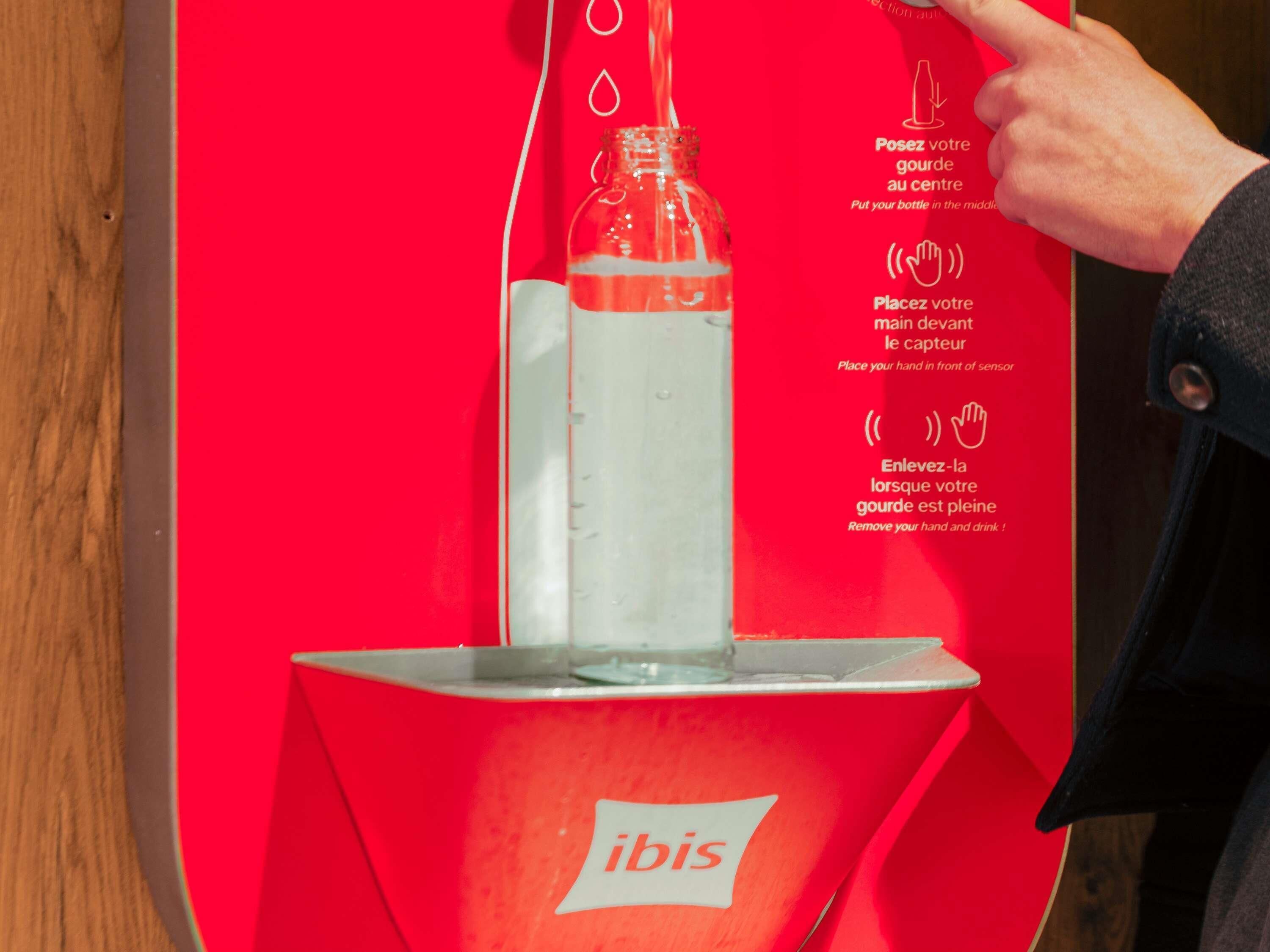 Un asiento rojo con una botella de agua e instrucciones en francés.