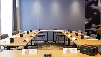Una sala conferenze con un lungo tavolo, sedie e una scatola nera con la scritta 'ibis meeting' sul pavimento.