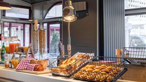 Een ontbijtbuffet met diverse gebakjes, brood en drankjes.