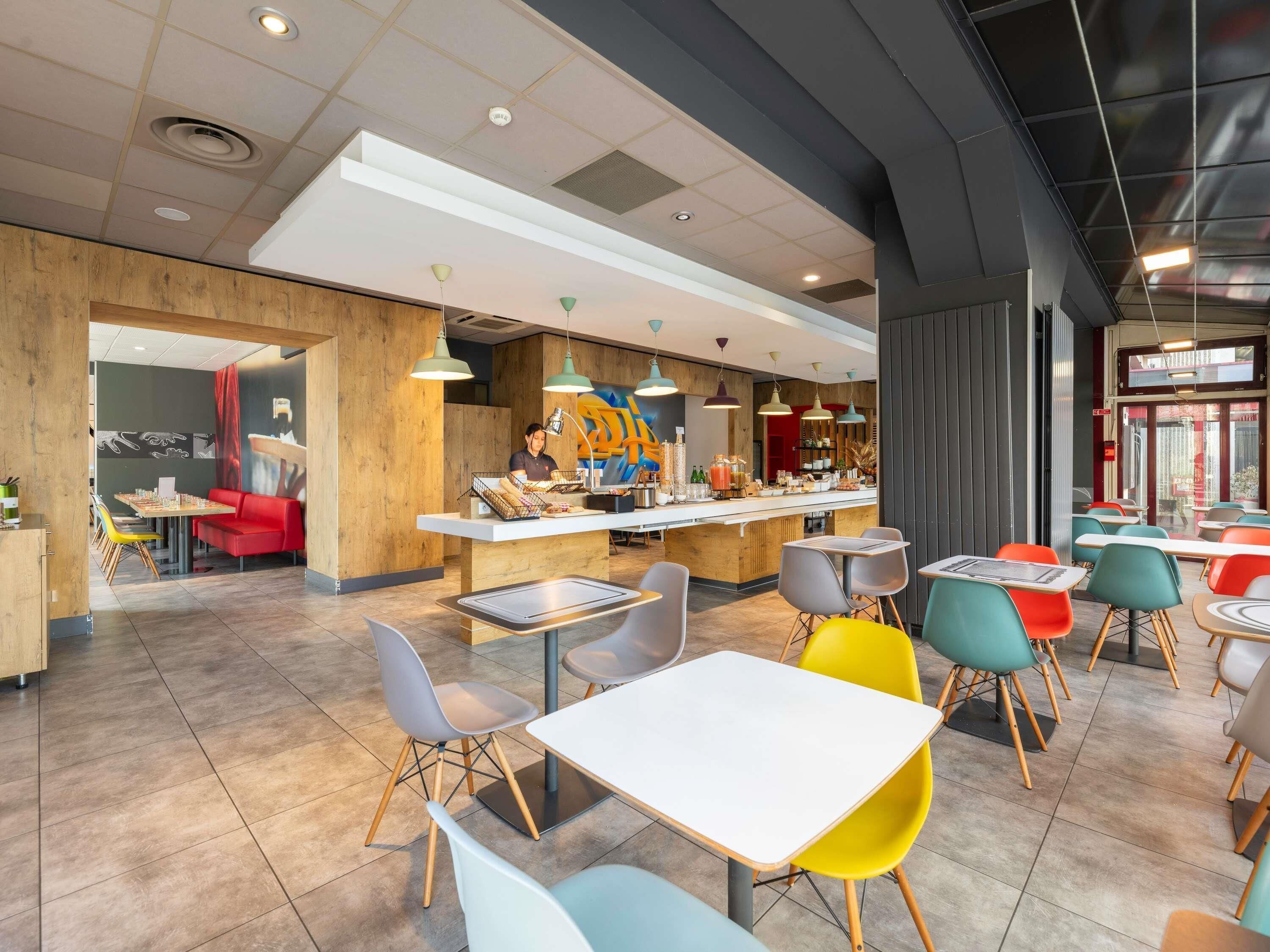Een modern café met een centrale balie, verschillende zithoeken en een diversiteit aan stoelen en tafels.