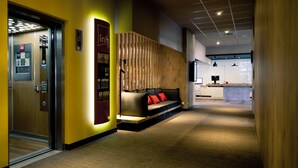 Een moderne hotel lobby met een receptiebalie, een zithoek met een bank en een houten accentmuur.