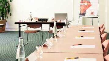 Un salón de conferencias con una larga mesa, sillas, tarjetas de identificación, botellas de agua y una computadora portátil.