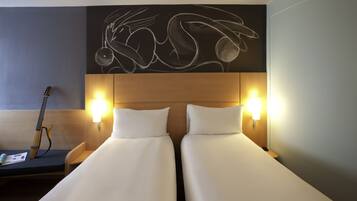 Habitación de hotel con dos camas, una guitarra y una obra de arte en la pared.