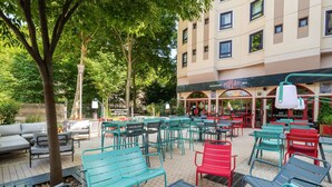 Een terras met tafels en stoelen, een gebouw met restaurant 