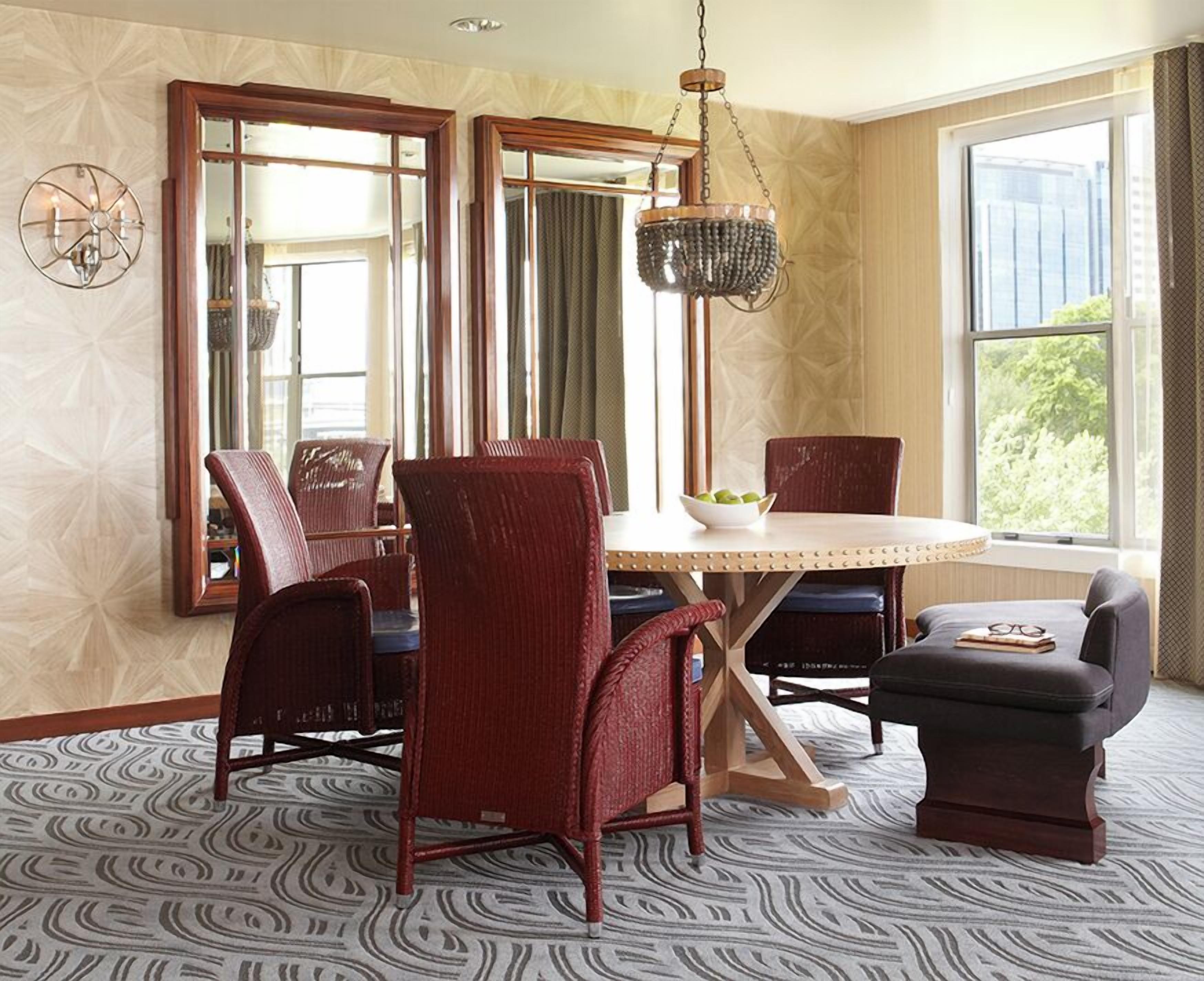 A dining area with a round table, four chairs, a small table, and a hanging light fixture.