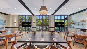 A conference room with a large table, chairs, and a view of trees through large windows.