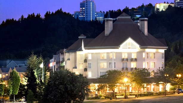 A large, illuminated hotel with a prominent central building and a boat docked nearby.