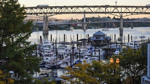 A marina with boats docked, a bridge in the background, and a building with a blue roof.