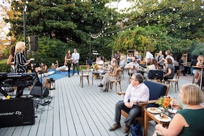 Un événement en plein air avec une installation de DJ, des tables, des chaises et des invités.