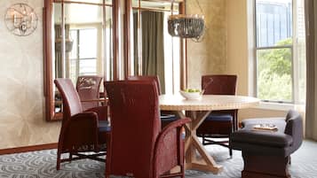 Un comedor con una mesa de madera, sillas de mimbre rojo y una lámpara colgante.