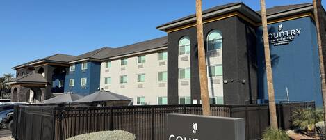 Edificio de Country Inn & Suites con un cartel, una entrada con portón y un césped bien cuidado.