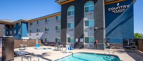 Un hotel con zona de piscina, mobiliario exterior y un cartel de Country Inn & Suites by Radisson.