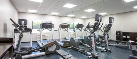 A gym with various exercise machines, a water dispenser, and a mirrored wall.