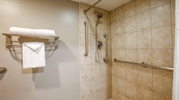 A walk-in shower with a grab bar, a towel rack with two towels, and a showerhead.