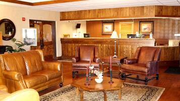 A lobby with leather sofas, a wooden reception desk, and a reception area with a computer and framed pictures.