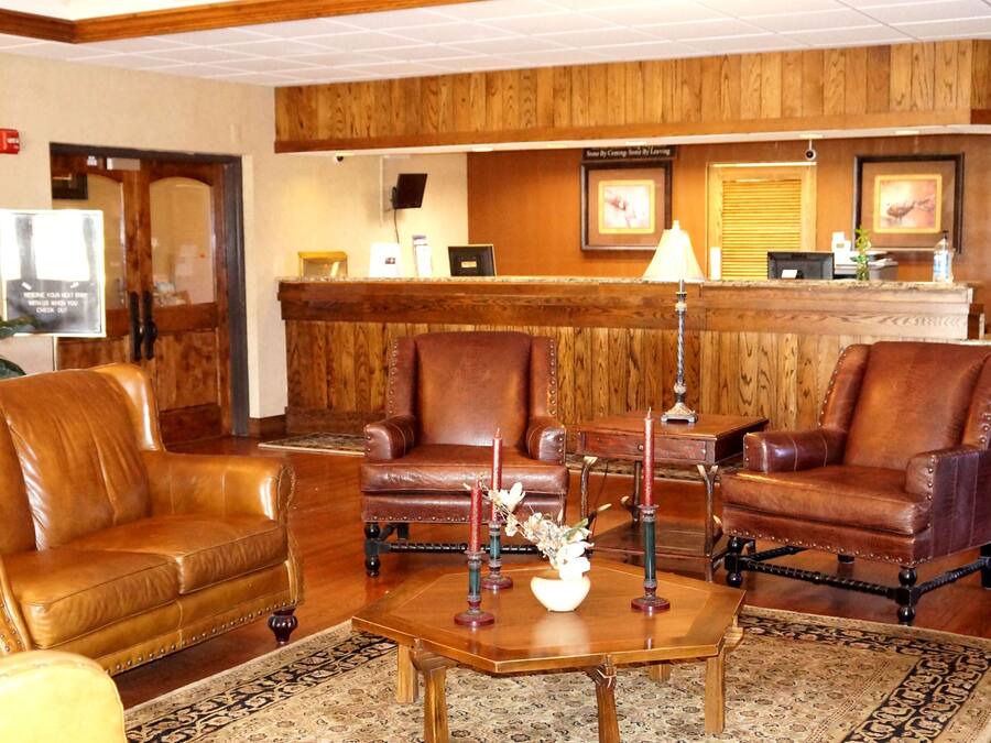 A lobby with leather sofas, a wooden reception desk, and a reception area with a computer and framed pictures.