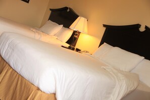 A hotel room with a large bed, a bedside lamp, and a nightstand.